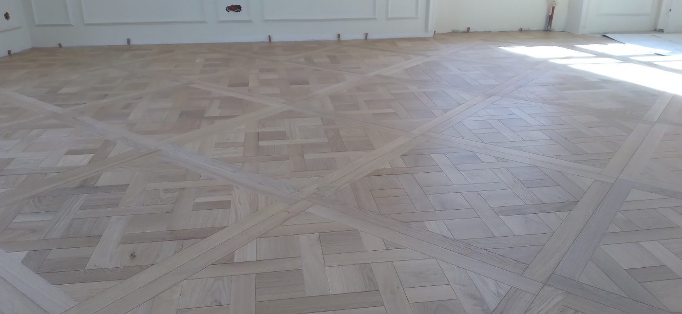 Parquet Versailles gros plan motif entrelacé chêne massif Île-de-France